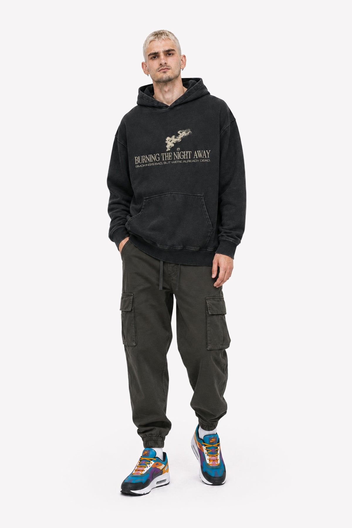 Mann trägt einen acid wash oversized hoodie mit dem Schriftzug 'BURNING THE NIGHT AWAY', kombiniert mit Cargo-Hosen.